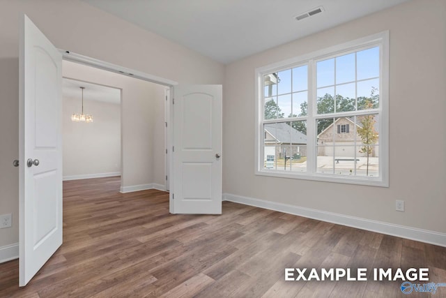 unfurnished bedroom featuring an inviting chandelier and wood-type flooring