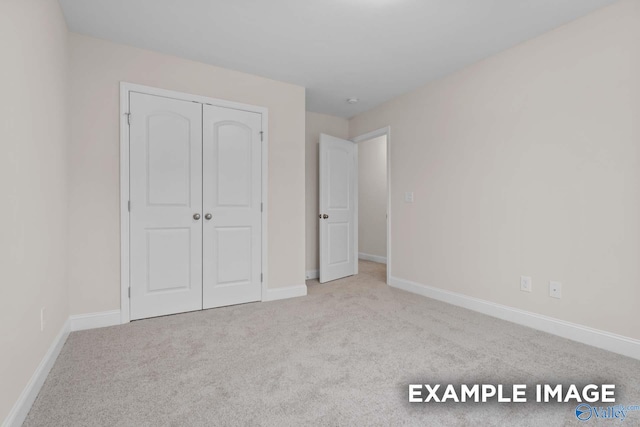 unfurnished bedroom featuring light colored carpet and a closet