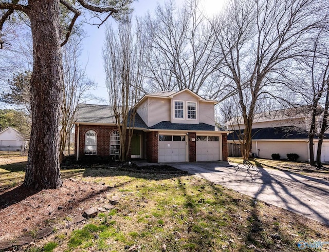 traditional-style house featuring an attached garage, driveway, fence, and brick siding