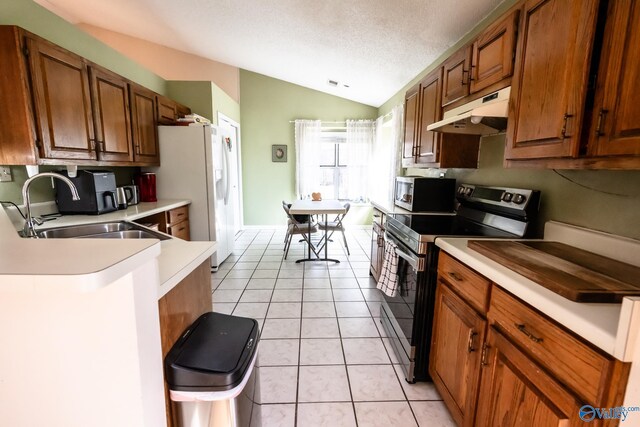 kitchen featuring light tile patterned floors, under cabinet range hood, stainless steel appliances, a sink, and vaulted ceiling