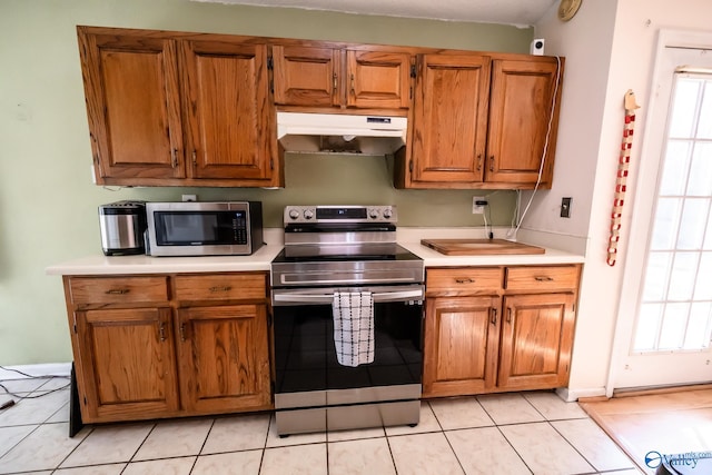 kitchen with appliances with stainless steel finishes, brown cabinets, light countertops, and under cabinet range hood