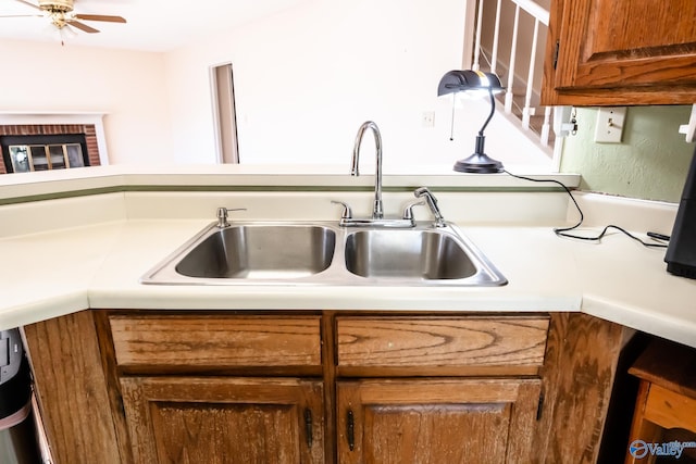 kitchen with light countertops, brown cabinetry, a sink, and a ceiling fan