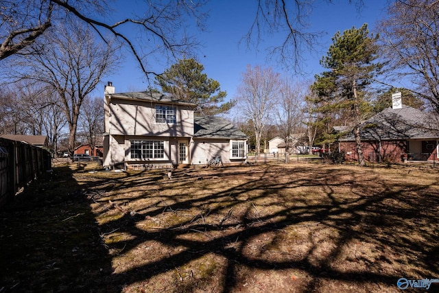 view of side of home with a chimney and fence