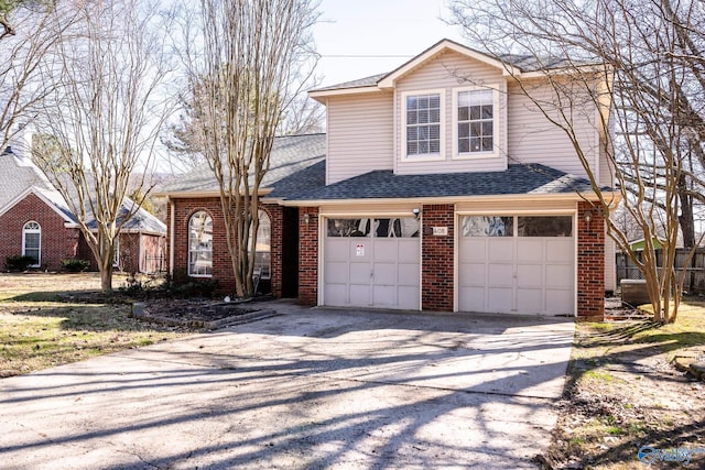 traditional-style home featuring a shingled roof, brick siding, driveway, and a garage