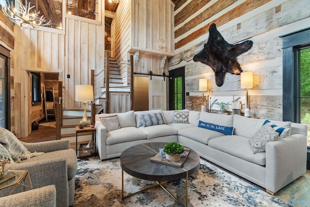 511 Pine Island Cir, Scottsboro, AL 35769 - living area with wood walls, high vaulted ceiling, a chandelier, a barn door, and wood finished floors
