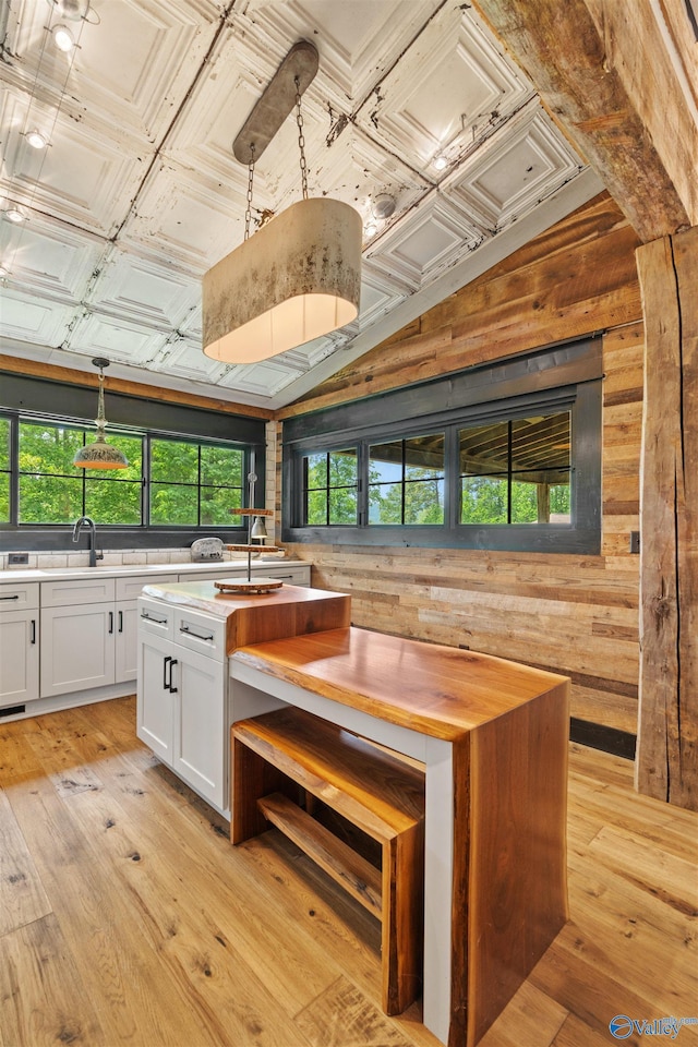 511 Pine Island Cir, Scottsboro, AL 35769 - kitchen featuring wood walls, white cabinetry, decorative light fixtures, light wood-type flooring, and a sink