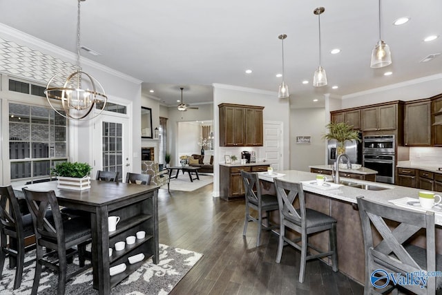 dining area with ornamental molding, sink, dark wood-type flooring, and ceiling fan with notable chandelier