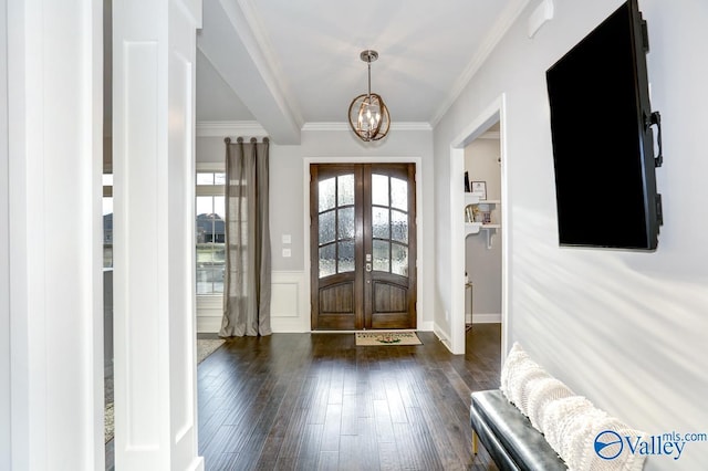 foyer featuring dark hardwood / wood-style flooring, a notable chandelier, crown molding, and french doors