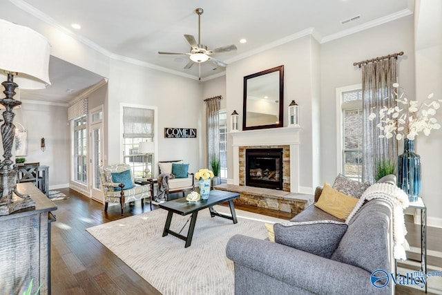 living room with ornamental molding, a stone fireplace, and dark hardwood / wood-style floors