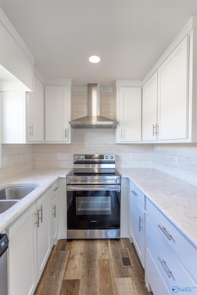 kitchen featuring appliances with stainless steel finishes, white cabinets, decorative backsplash, dark wood-type flooring, and wall chimney exhaust hood