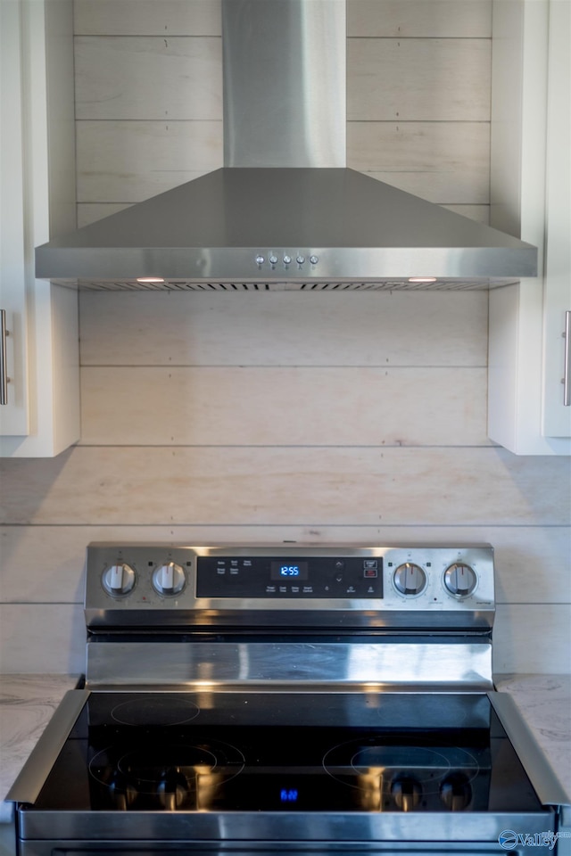 details featuring electric range and wall chimney exhaust hood