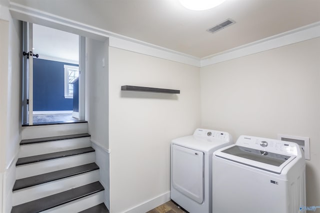 clothes washing area with light wood-type flooring, washer and dryer, and ornamental molding