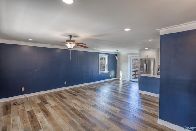 unfurnished living room featuring ceiling fan, hardwood / wood-style flooring, and ornamental molding