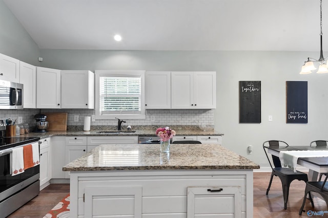 kitchen with appliances with stainless steel finishes, a center island, hanging light fixtures, and sink