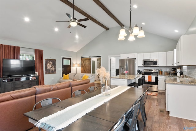 dining area with sink, a barn door, beam ceiling, high vaulted ceiling, and dark hardwood / wood-style floors