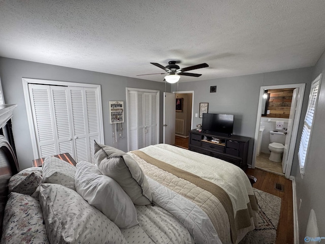 bedroom featuring a ceiling fan, wood finished floors, a textured ceiling, and two closets