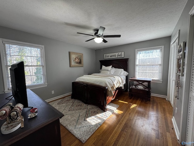 bedroom with a textured ceiling, ceiling fan, dark wood-style flooring, and baseboards