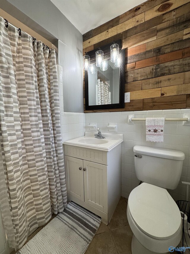 bathroom with tile walls, toilet, wainscoting, vanity, and tile patterned flooring