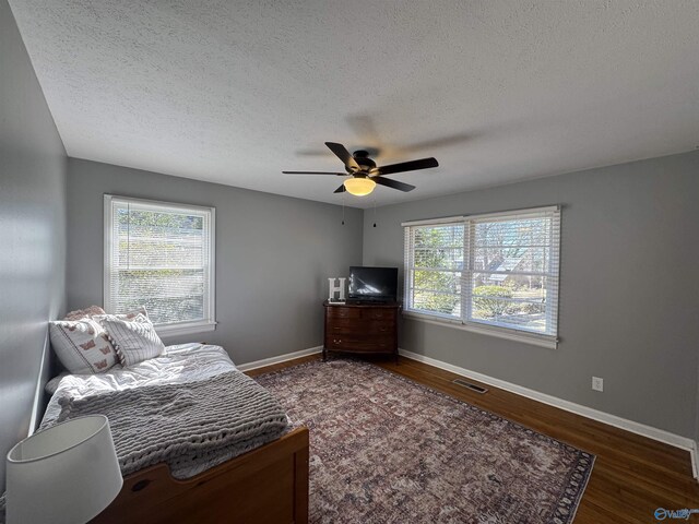 bedroom with baseboards, multiple windows, visible vents, and wood finished floors