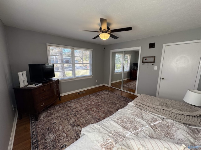 bedroom featuring a textured ceiling, wood finished floors, a ceiling fan, visible vents, and baseboards