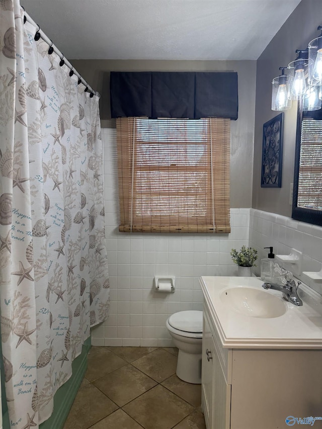 bathroom with tile patterned flooring, toilet, a shower with shower curtain, vanity, and tile walls