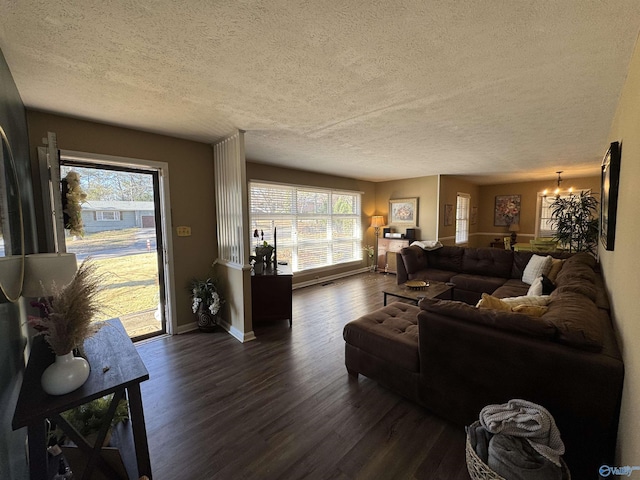 living area featuring baseboards, a textured ceiling, a chandelier, and dark wood-type flooring