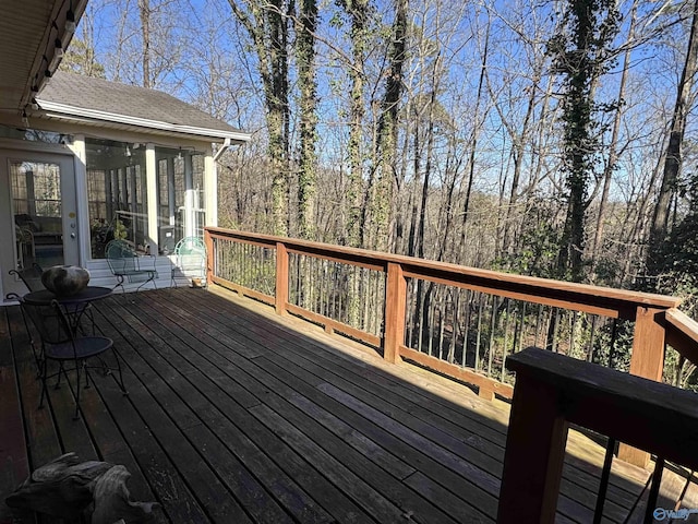 wooden deck featuring a sunroom and a view of trees