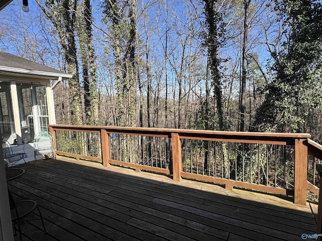 deck with a sunroom and a view of trees