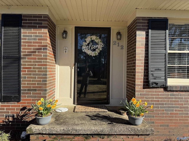 view of exterior entry featuring brick siding