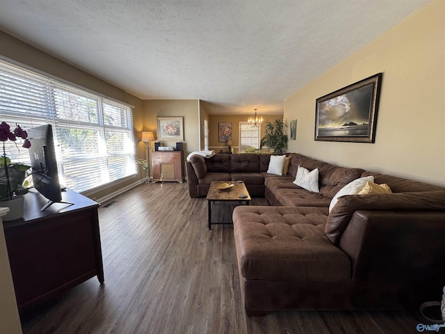 living room featuring a textured ceiling, dark wood-type flooring, a chandelier, and visible vents