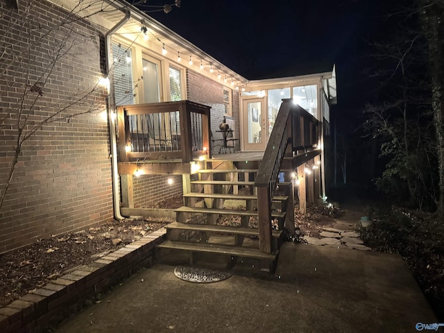 exterior space featuring brick siding, a deck, and stairs