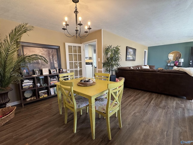 dining space featuring dark wood-style floors, a textured ceiling, baseboards, and an inviting chandelier