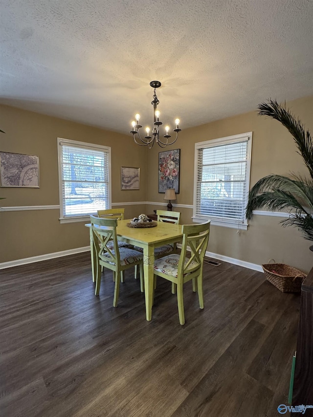 dining space with dark wood-style floors, a notable chandelier, and a textured ceiling