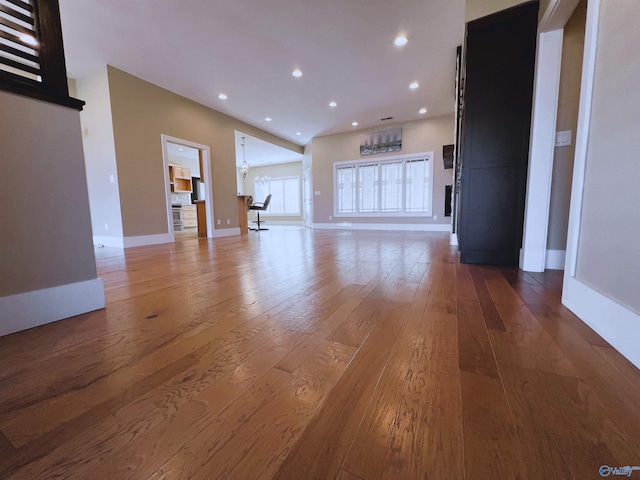 unfurnished living room featuring recessed lighting, baseboards, and hardwood / wood-style flooring