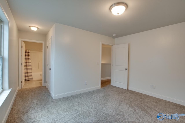 unfurnished bedroom with a closet, a spacious closet, and light colored carpet