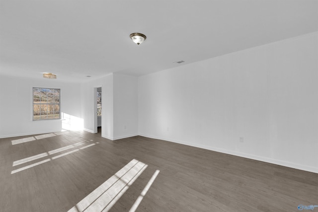 empty room featuring visible vents, baseboards, and wood finished floors