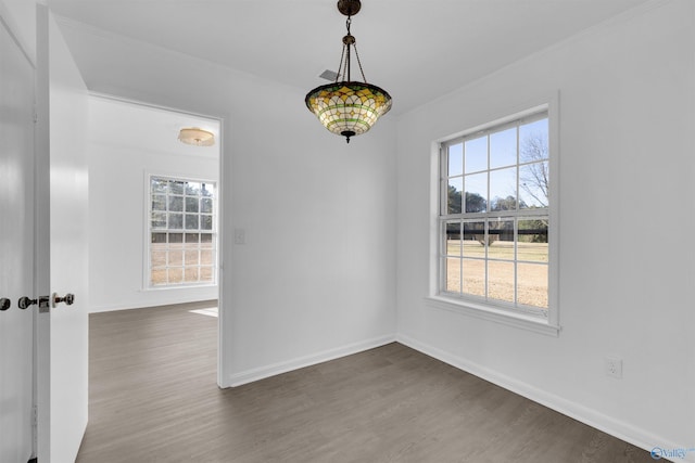 unfurnished dining area featuring crown molding, dark wood finished floors, and baseboards