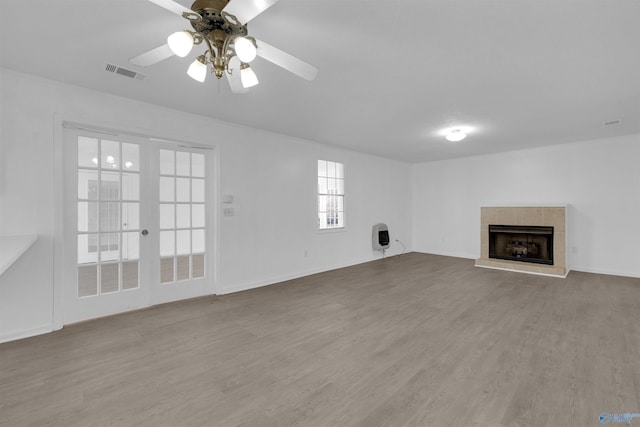 unfurnished living room with heating unit, visible vents, ceiling fan, wood finished floors, and a tile fireplace