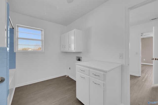 clothes washing area with cabinet space, visible vents, a ceiling fan, and wood finished floors