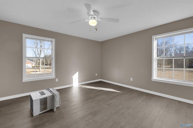 empty room with dark wood-type flooring, baseboards, and a ceiling fan