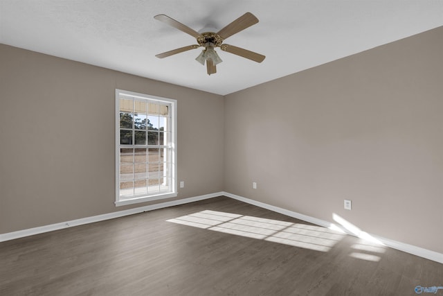 unfurnished room featuring dark wood-style floors, baseboards, and a ceiling fan