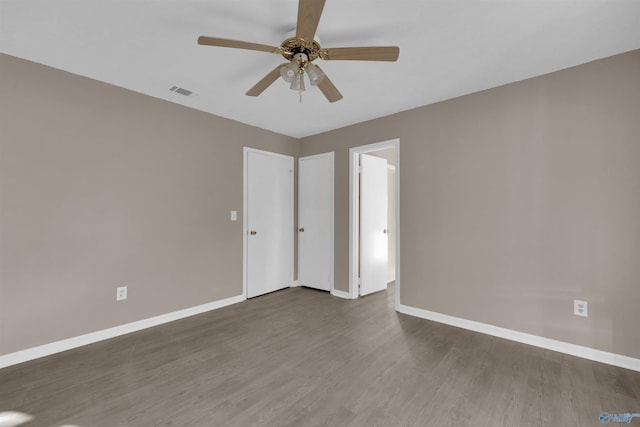 unfurnished room with wood finished floors, visible vents, and baseboards