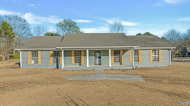 ranch-style house featuring a porch, brick siding, and roof with shingles