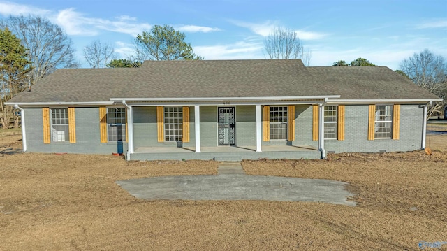 ranch-style house featuring roof with shingles, a porch, and brick siding