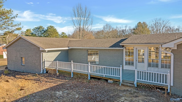 view of front of property featuring roof with shingles, a wooden deck, and brick siding