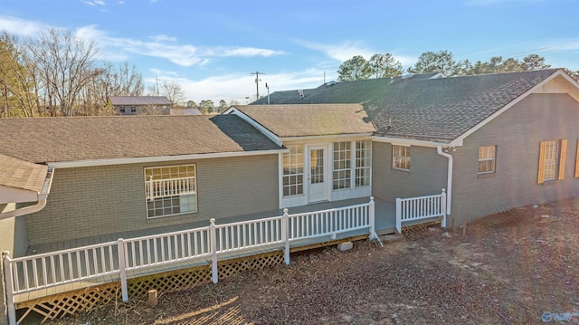 rear view of house featuring brick siding, roof with shingles, and a wooden deck