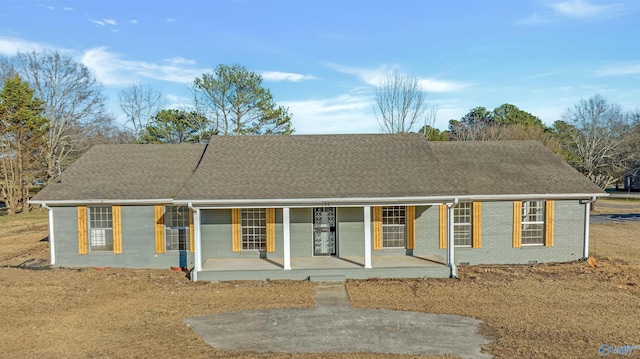 single story home with a porch, a shingled roof, and brick siding