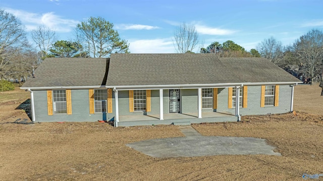 view of front of house featuring a shingled roof, a porch, and brick siding