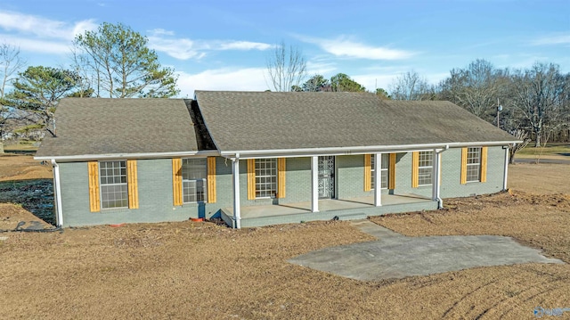 single story home featuring a porch, brick siding, and roof with shingles