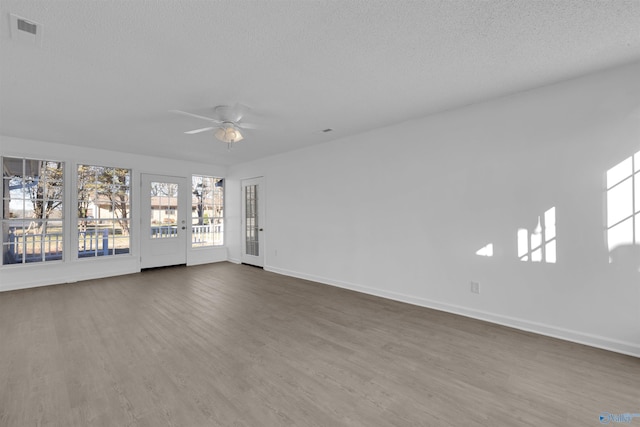 spare room featuring dark wood-style floors, visible vents, a ceiling fan, a textured ceiling, and baseboards